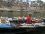 A man selling local provisions and trinkets from his floating boat store, on the Ganges river.